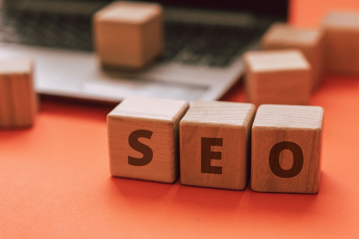 Wooden blocks spelling SEO on a desk next to a laptop, representing local search optimization