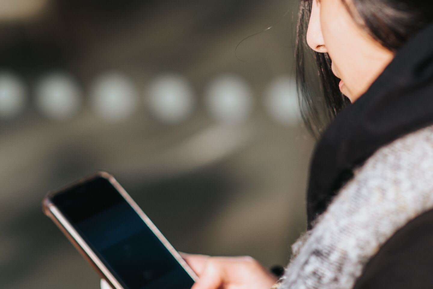 Woman waiting for a website to load on her phone while standing outside